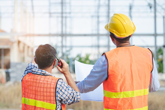 Asian engineer using radio to command to labour team in site construction.