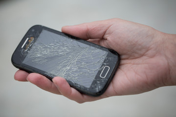 Broken glass screen smartphone in hand.Hand holding mobile phone with broken screen. Smartphone with cracked display in hand.Hand hold the cellular.