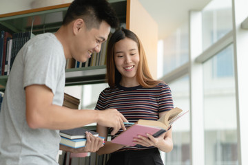 Two asian students researching for project in library.