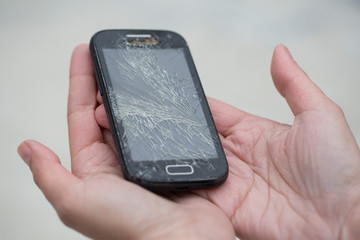 Broken glass screen smartphone in hand.Hand holding mobile phone with broken screen. Smartphone with cracked display in hand.Hand hold the cellular.
