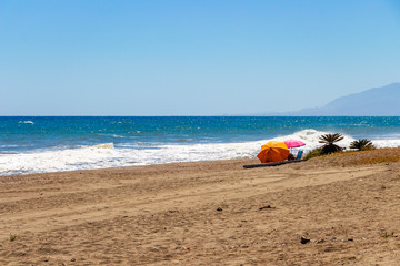 Fototapeta na wymiar Two sun umbrellas on a sandy beach at Torre de Benagalbon, Province of Malaga, Andalusia, Spain