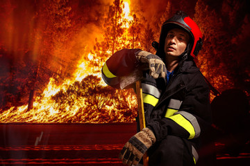 Frontal view of a firefighter in action to extinguish the flame in forest.