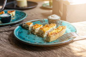 Chicken Quiche with mushrooms Recipe. Quiche Lorraine with chicken and Champignons and sauce on a blue plate on wooden table. Pie with chicken and mushrooms. Traditional French food