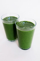 Fresh green kale, banana, coconut milk, spirulina and flax seeds smoothie on white background. Healthy food