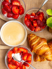 Plate of fresh croissant and cup of coffee on sackcloth background