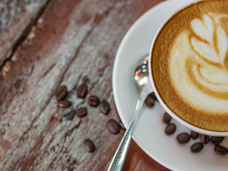 Cup of coffee and coffee beans on wooden table