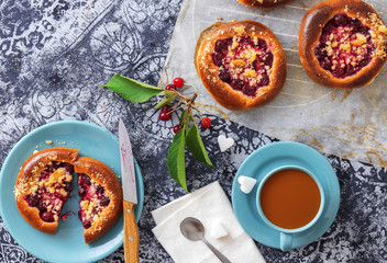 Table with yeasty sweet pastry with fresh cherries and streusel topping, cup of tea and few cubes of sugar. Summer fresh fruit appetizer.