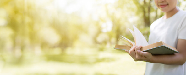 Read and knowledge concept, hand holding book on soft green park banner background