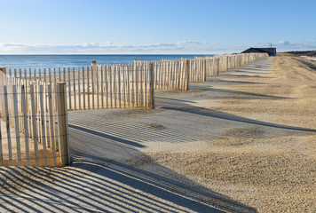 Fototapeta na wymiar Row of Beach Fences with Shadows in Sand