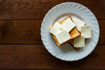 Plate with toasted bread isolated on wooden background, top view
