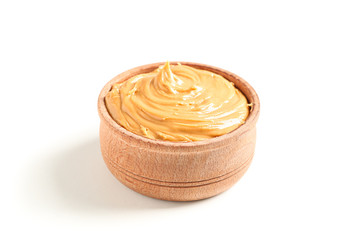 Creamy peanut butter in wooden bowl isolated on white background. A traditional product of American cuisine