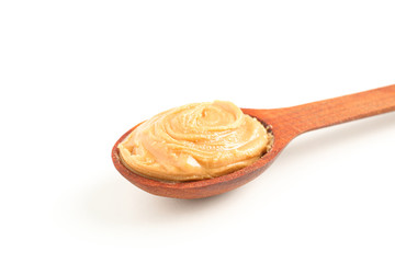 Creamy peanut butter in wooden spoon isolated on white background, closeup. A traditional product of American cuisine