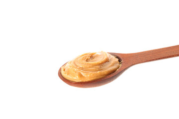 Creamy peanut butter in wooden spoon isolated on white background, closeup. A traditional product of American cuisine