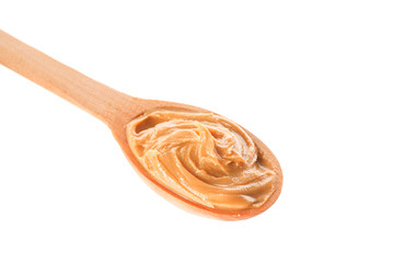 Creamy peanut butter in wooden spoon isolated on white background, closeup. A traditional product of American cuisine