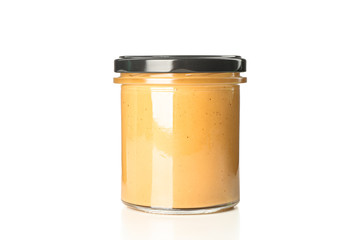 Creamy peanut butter in glass jar isolated on white background. A traditional product of American cuisine