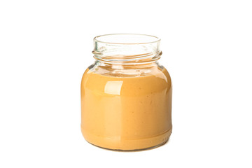 Creamy peanut butter in glass jar isolated on white background. A traditional product of American cuisine