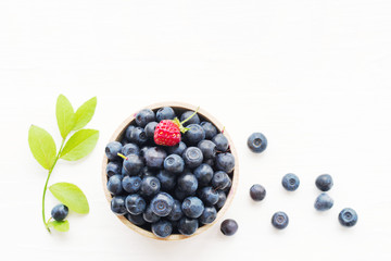 Fresh bilberry in a wooden bowl on a white background, top view