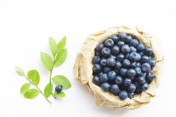 Fresh bilberry in a wooden bowl on a white background, top view