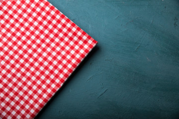 Empty wooden deck table and red checked tablecloth over mint wallpaper background