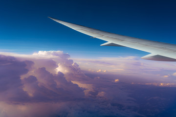 Scenic sky view from the airplane window. Beautiful pink clouds and airplane wing. Travel concept
