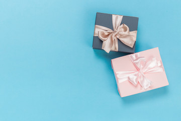 Obraz na płótnie Canvas beautiful gift boxes wrapped in paper with gold and pink ribbon on a blue surface. Top view