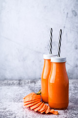 two glass bottle with carrot smoothie