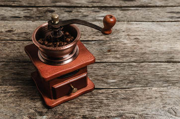 Hand coffee grinder with coffee beans on wooden background.