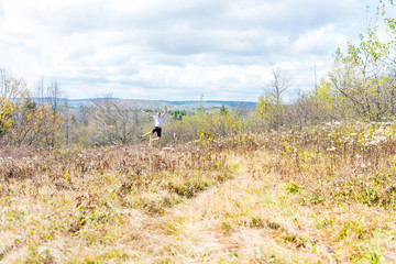 Young athletic, fit, free happy man running jogging jumping in autumn, fall, summer meadow field path hike in mid-air, muscles, front