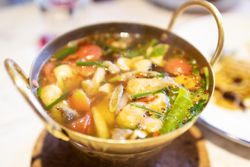 Hot and spicy soup with a straw mushroom in brass pan. Delicious Thai food.