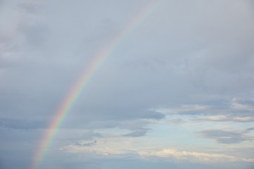 rainbow on blue sky background with white clouds