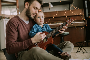 Obraz premium A man is teaching a little girl to play the guitar