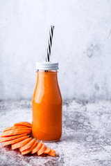 glass bottle with carrot smoothie on table