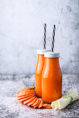 two glass bottle with carrot and celery smoothie on table
