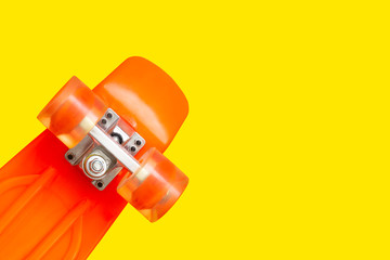 Sport background with copy space. Orange plastic mini cruiser skateboard on yellow. minimalist flat lay photo.