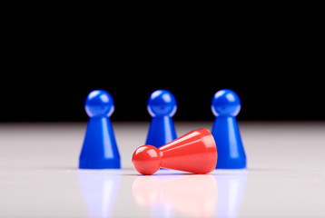 Standing three blue game pieces as winner and lying red figurine as loser on white table top with black background - Space for your text.