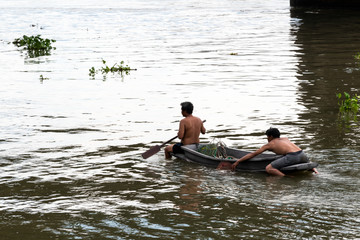 Two fishermen are rowing in the river.