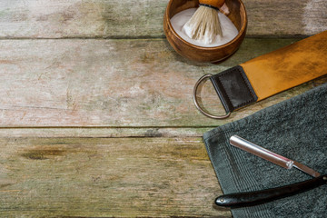 Vintage straight razor, leather strop and shaving brush. Old-school wet shaving in rustic wooden table, with copy space.