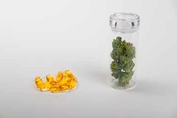 Side view, glass jar with cannabis buds next to thc pills