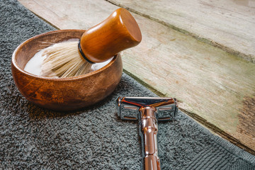 Shiny safety razor, shaving brush and lather in bowl. Old-school wet shaving in rustic wooden...