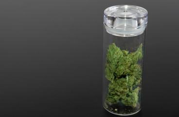 Side view, glass jar with cannabis buds on black background