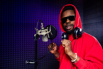 afro american man headphones in a cap and a hood sunglasses recording hip hop song track.
