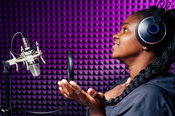afro american woman with pigtails hairstyle headphones in a cap and a hood sunglasses recording hip hop song track.