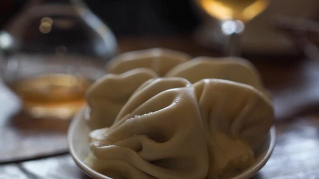Close up of spinning plate of delicious khinkali dumplings seasoned with chili pepper