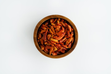 Dried bird's eye chili peppers in a wooden bowl. White background, high resolution