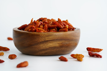 Dried bird's eye chili peppers in a wooden bowl. White background, high resolution