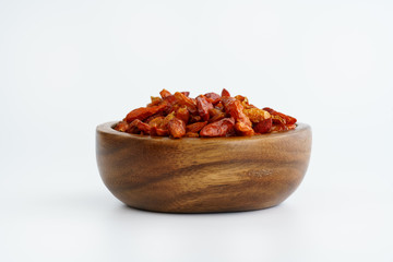 Dried bird's eye chili peppers in a wooden bowl. White background, high resolution