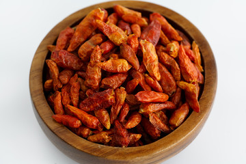 Dried bird's eye chili peppers in a wooden bowl. White background, high resolution