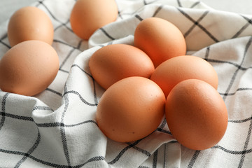 Brown chicken eggs in kitchen towel, space for text and closeup