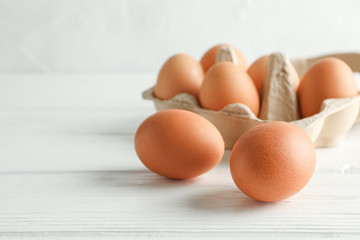 Brown chicken eggs in carton box on white background, space for text and closeup