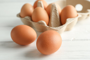 Brown chicken eggs in carton box on white background, space for text and closeup